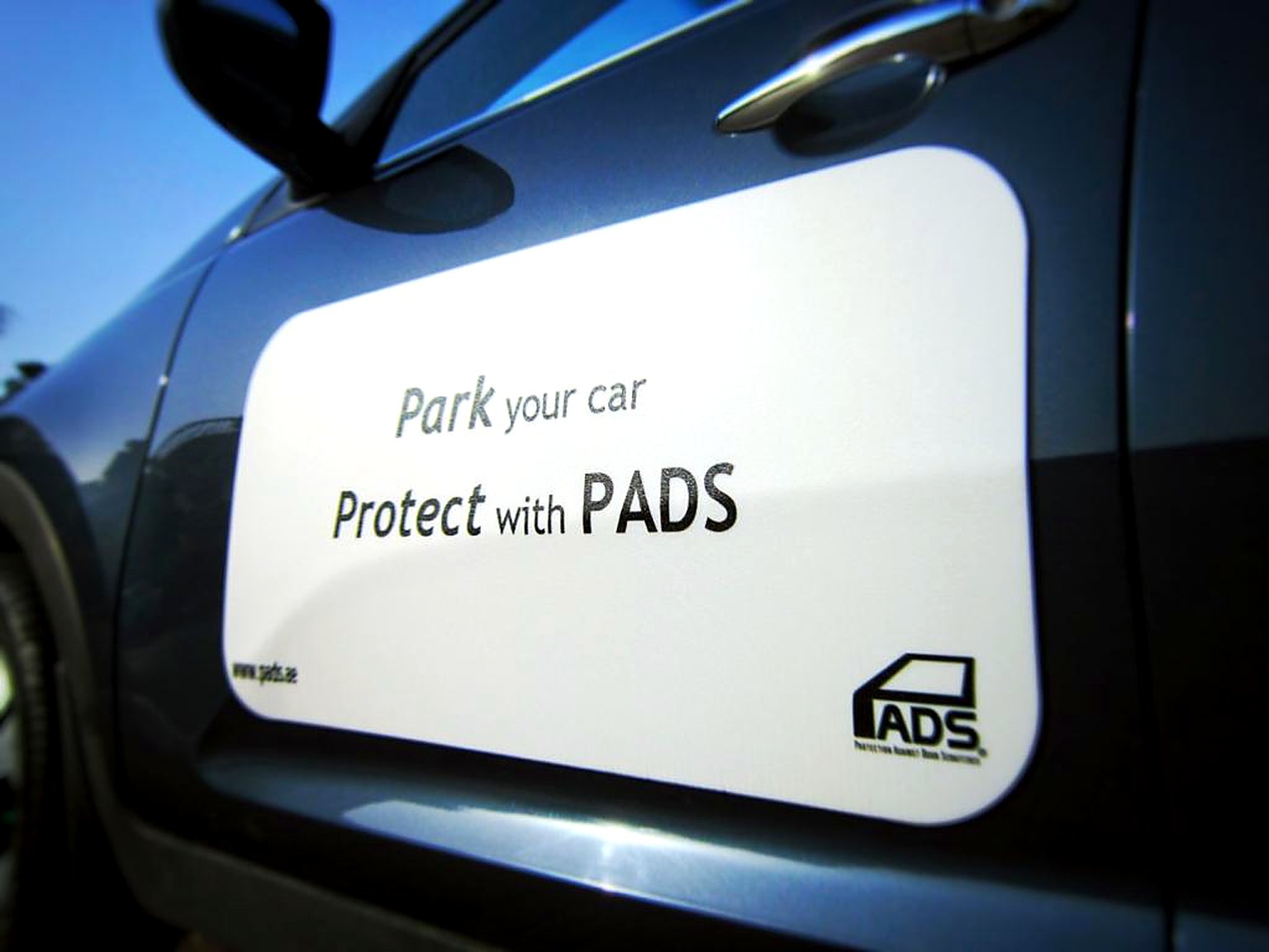 White PADS on a car door reading Park your car, Protect with PADS